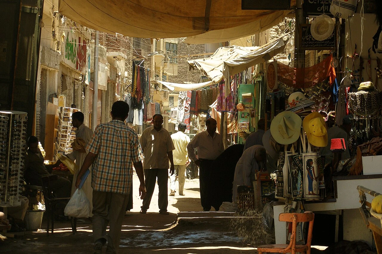 People walking through a shaded Aswan shopping street